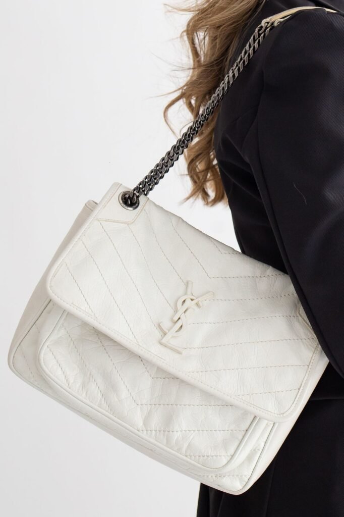 Mulher separando bolsa de luxo usada para vender na internet